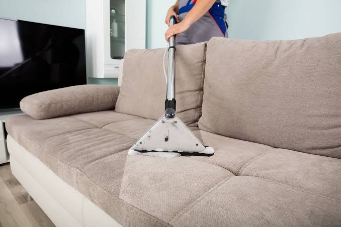 Profissional realizando higienização profunda de sofá